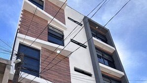 A multi-story building with a modern architectural style, featuring a combination of brick and white facade, large windows, and visible electrical wiring. - Hotel Felix (San Juan de los Lagos)