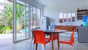 Una cocina moderna con refrigerador, dispensador de agua y un comedor con sillas rojas.