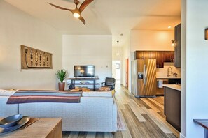 A modern living room with a sofa, a television, and a dining table with cutlery.