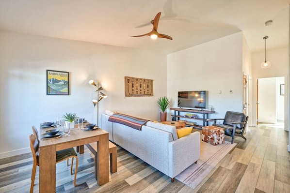 Un salon moderne comprenant un canapé, une table à manger, un téléviseur et un ventilateur de plafond.