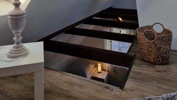 A room with a skylight, a lamp, a woven basket, and a macrame wall hanging.