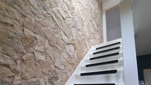 A staircase with black handrails and a stone wall on one side.