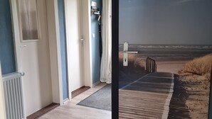 A room with a view of the beach, a door, a radiator, and a curtain.