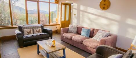 Un salon avec deux canapés, une table basse et une grande fenêtre donnant sur les montagnes.