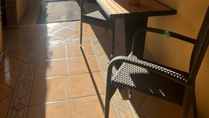 A sunlit room with a tiled floor, a table with chairs, a ceiling fan, and a door leading outside. - Ferienhof Eckhoff apartment no. 4 with south-facing terrace (Fehmarn)