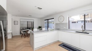 Una cocina moderna con una isla grande, muebles blancos y una ventana con vistas a un jardín.