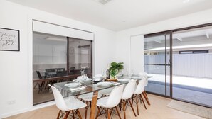 Un comedor moderno con una mesa de cristal, sillas blancas y una botella de champán.