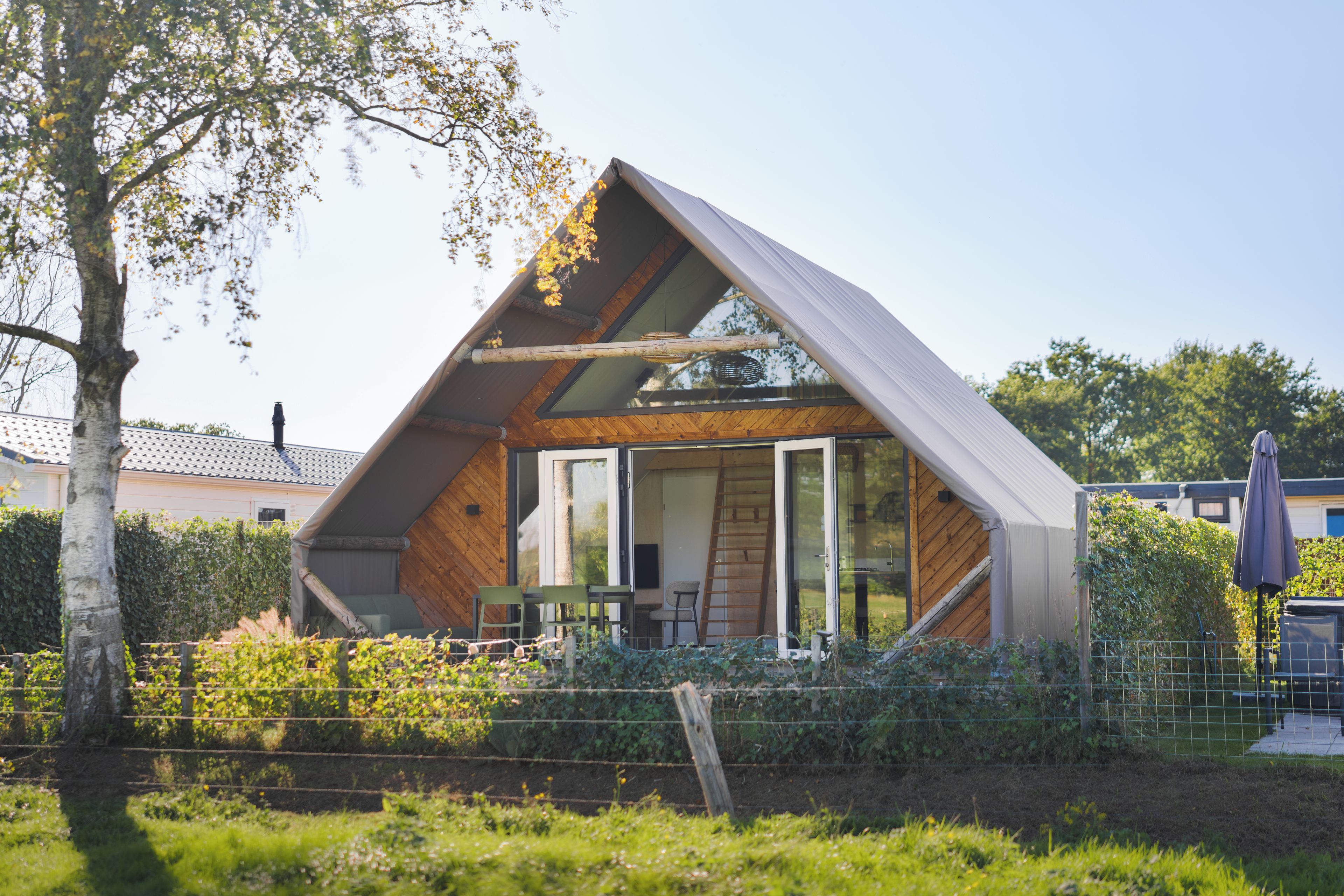 A modern house with a sloped roof, large windows, and a visible outdoor seating area.
