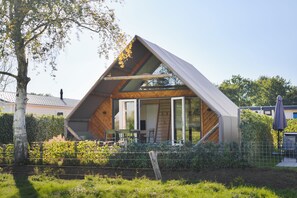 Une maison moderne dotée d’un toit en pente, de grandes fenêtres et d’un espace extérieur aménagé pour se détendre.