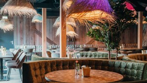 A cozy restaurant with round tables and cushioned seating, featuring thatched umbrellas and a rustic wooden interior. - Big lodge | 6 persons (Voorthuizen)