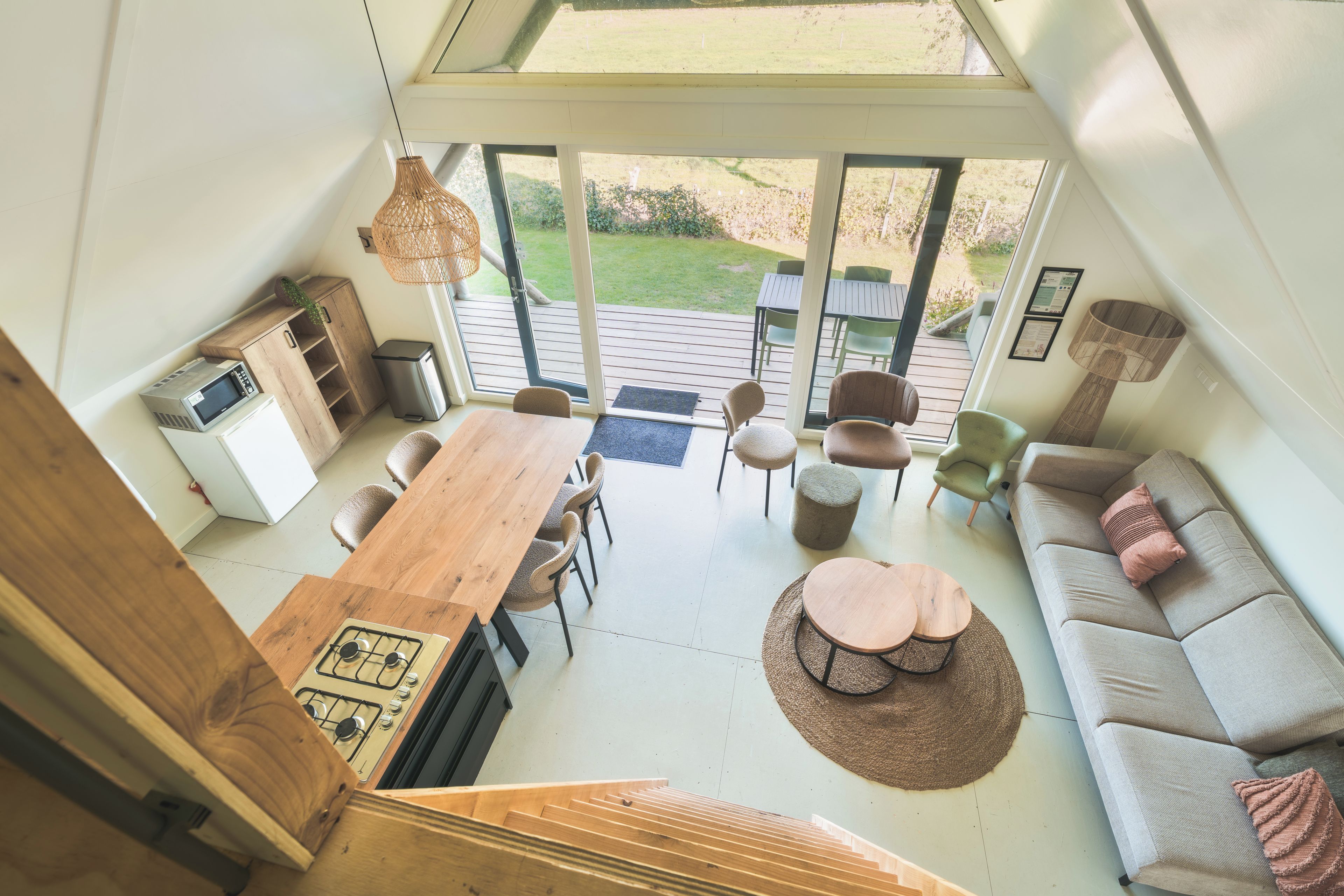 A modern interior with a dining area, kitchen, and seating space, featuring a large window and a staircase.