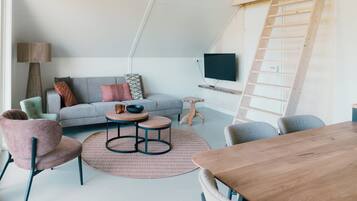 A modern living room with a grey sofa, round coffee table, and a wooden dining table.