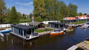 A marina with docked boats, a small house-like structure with a balcony, and a building with a red roof. - Safari tent Heeg 4 persons (Heeg)
