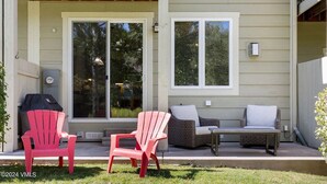 A covered patio with two Adirondack chairs, a wicker sofa, and a small table. - 4 bedroom Eagle Vail townhome on golf course; minutes to Vail and Beaver Creek (Avon)