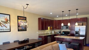 A modern kitchen with dark wooden cabinets, stainless steel appliances, and a granite countertop. - 4 bedroom Eagle Vail townhome on golf course; minutes to Vail and Beaver Creek (Avon)