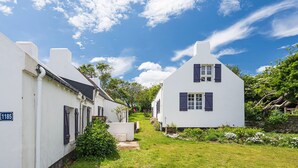 A row of white houses with dark shutters, a clear blue sky, and lush greenery. - Samzun, close to the beach, garden & sea view (Bangor)