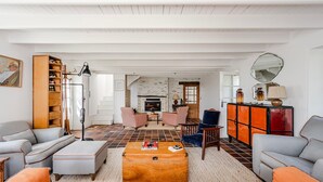 A living room with a fireplace, a wooden cabinet, and a large mirror on the wall. - Samzun, close to the beach, garden & sea view (Bangor)