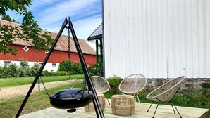 A wooden deck with a black swing set, wicker chairs, and a small table.