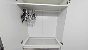 A white storage unit with multiple compartments, including a hanging rack for tools and a drawer with multiple trays.
