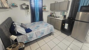 A compact living space with a bed, kitchenette, and a small dining area.
