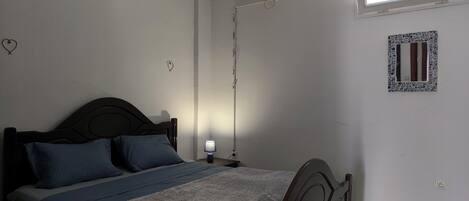 Un dormitorio con cama, lámpara de noche y ventana.