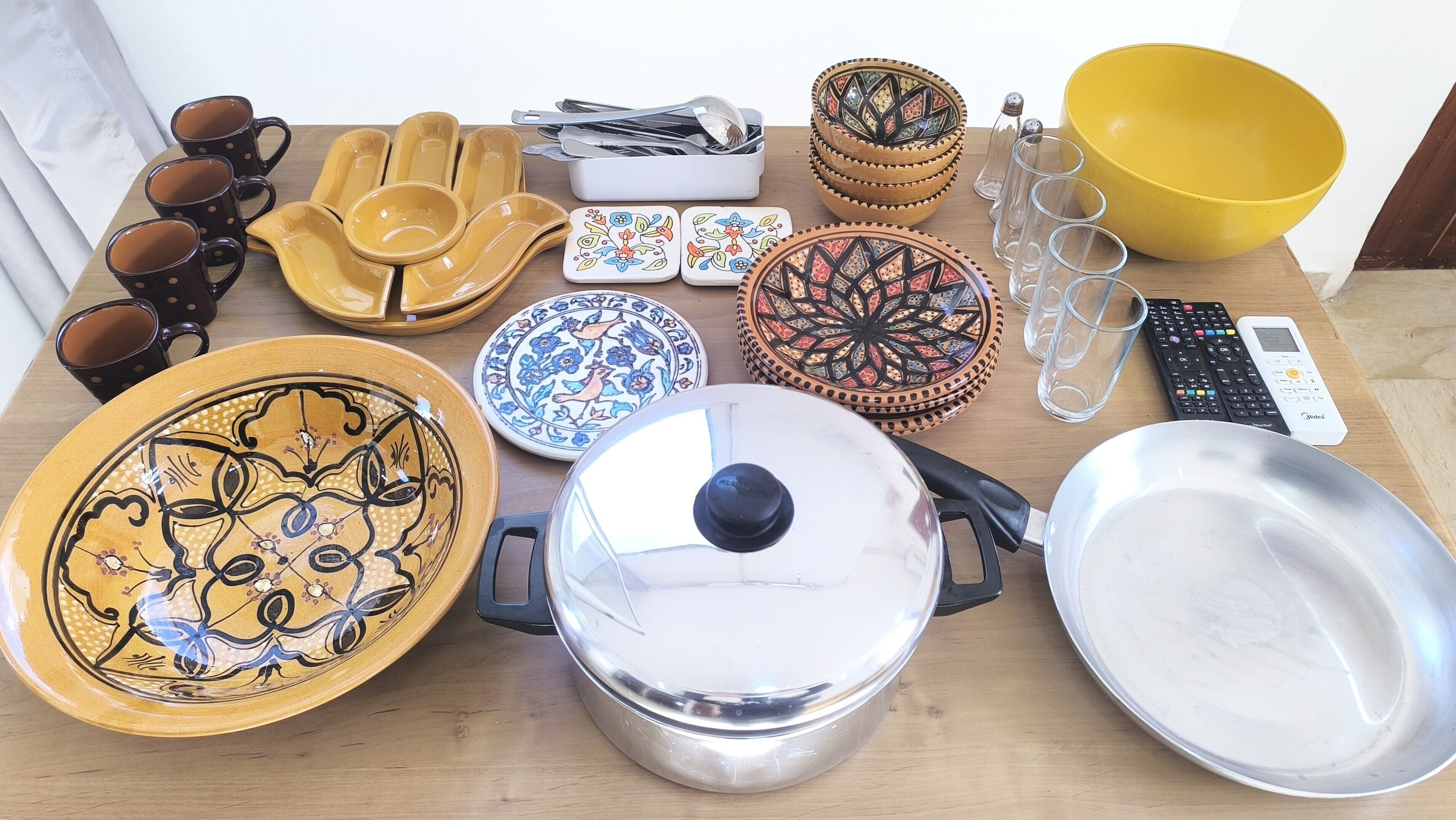 A table with various kitchenware items including plates, bowls, cups, and utensils.