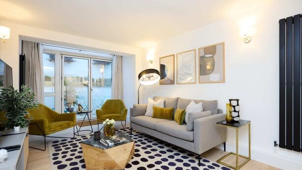 A modern living room with a grey sofa, two green armchairs, a coffee table, and a patterned rug. - The Melbray Gem - 2bdr Apartment With Courtyard (London)
