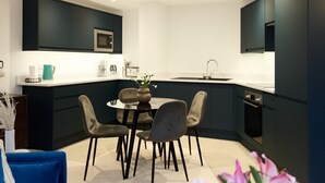 A modern kitchen with dark cabinetry, a round dining table, and four chairs. - The Melbray Escape - Trendy 2bdr Apartment (London)