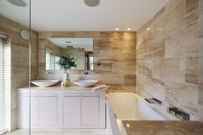 Un baño moderno con dos lavamanos, un espejo grande y una bañera.