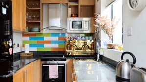 A modern kitchen with wooden cabinets, a microwave, a coffee machine, and a kettle. - The Shoreditch Retreat - Inviting 2bdr Apartment (London)