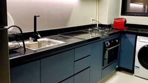 Une cuisine moderne équipée d’un four à micro-ondes, d’un évier, d’une cuisinière et d’un lave-linge.