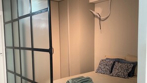 Een slaapkamer met een bed, een schuifdeur en een plafondlamp.