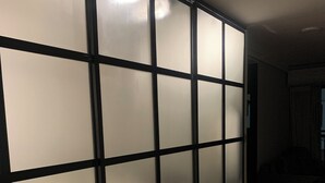 Une pièce dotée d’une porte coulissante de type shoji, d’un plancher en bois et d’une porte visible donnant sur une autre pièce.