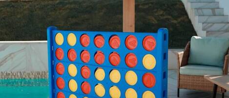 A board game setup outdoors with a pool and a covered seating area.