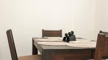 Une table à manger avec des sets de table, des bougies et un objet noir posé sur la table.