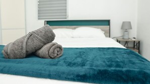 Ein Bett mit einer türkisfarbenen Bettdecke und zwei aufgerollten Handtüchern darauf.
