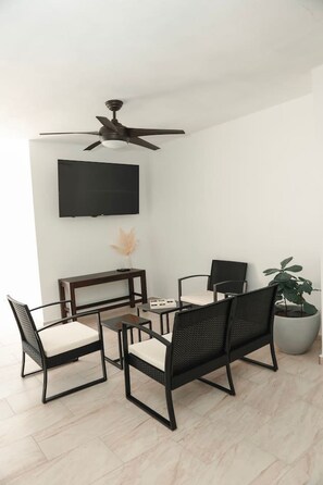 Ein moderner Essbereich mit Deckenventilator, flachbildfernseher an der Wand und einer Topfpflanze.