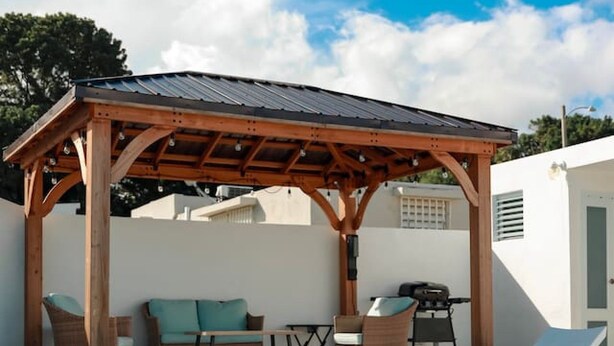 Ein Poolbereich mit Holz-Pergola, Liegestühlen und einem Tisch.