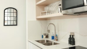 Une cuisine moderne avec des armoires blanches, un évier en acier inoxydable et un four à micro-ondes encastré.