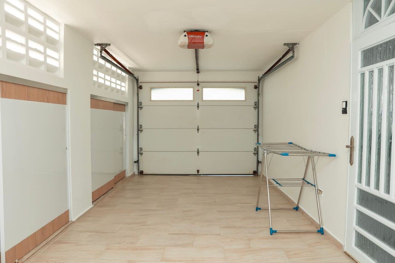 Un garage propre et dégagé, avec un étendoir métallique et un extincteur fixé au plafond.