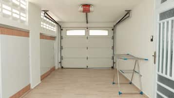 Un garage propre et dégagé, avec un étendoir métallique et un extincteur fixé au plafond.