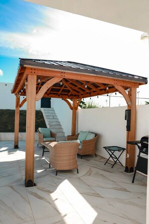 A covered outdoor seating area with wooden furniture and a pergola structure.