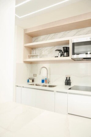 A modern kitchen with white cabinetry, a stainless steel sink, and a built-in microwave.