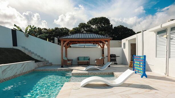 Une piscine dotée d’une pergola, de chaises longues et d’un toboggan.