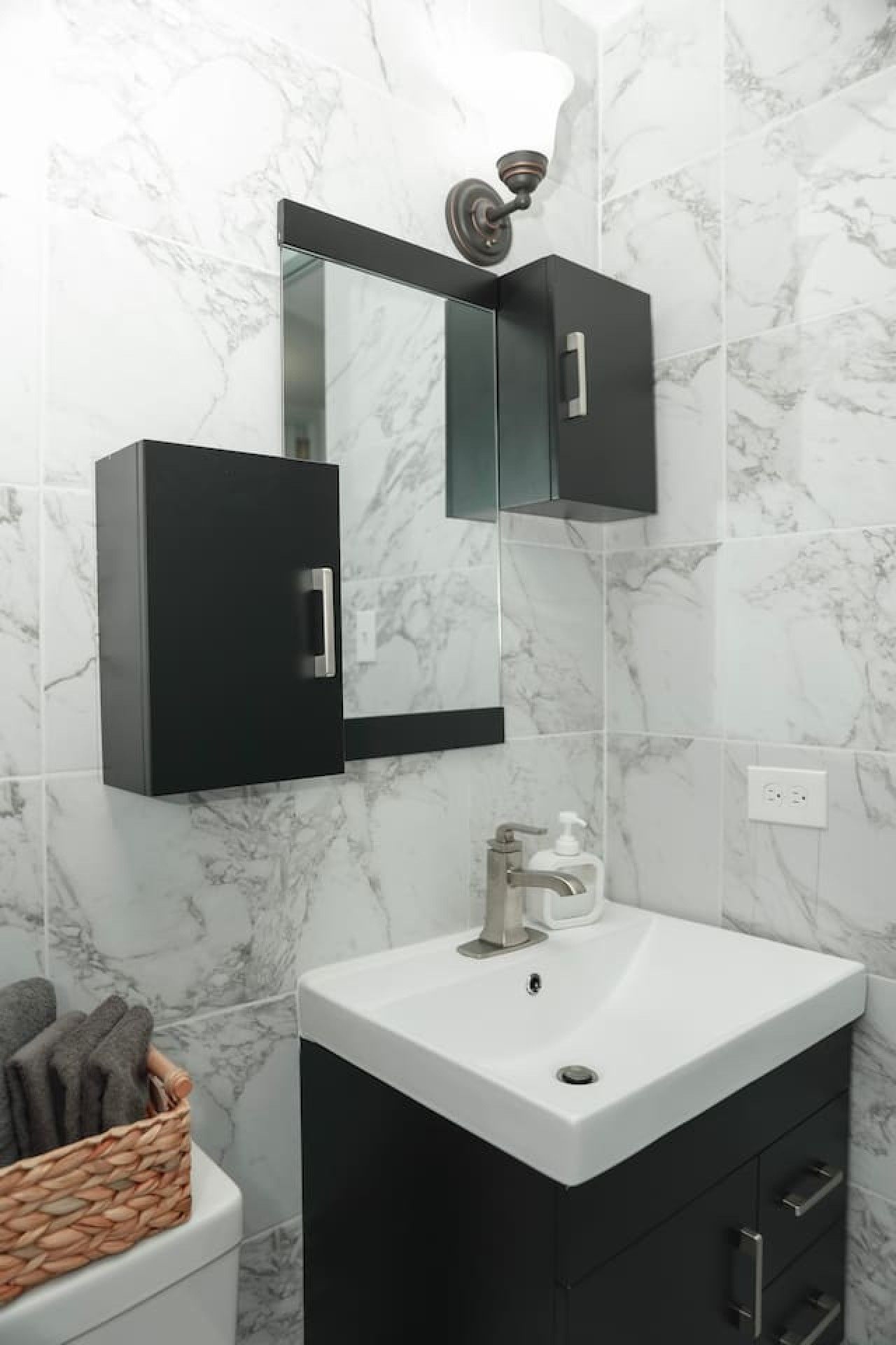 A bathroom with a white sink, black cabinet, and a mirror above the sink.
