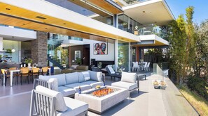 Ein moderner, offener Wohnbereich mit Kamin, Sitzgelegenheiten und einer Glasstairnase.
