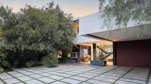 A modern house with a paved courtyard, a staircase leading to an upper level, and surrounding greenery. - Hollywood Overlook by Avantstay Private Pool + Hot Tub Panoramic Views (Los Angeles)
