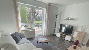 Ein modernes Wohnzimmer mit Sofa, Couchtisch, Fernseher und Essbereich.