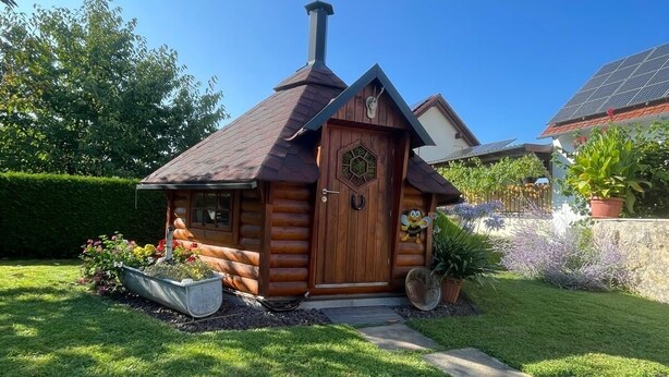 Eine Blockhütte mit Schornstein, umgeben von einem gepflegten Rasen und Garten.