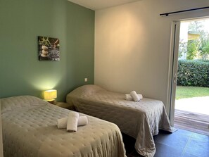 A room with two beds, a painting on the wall, and a lamp.